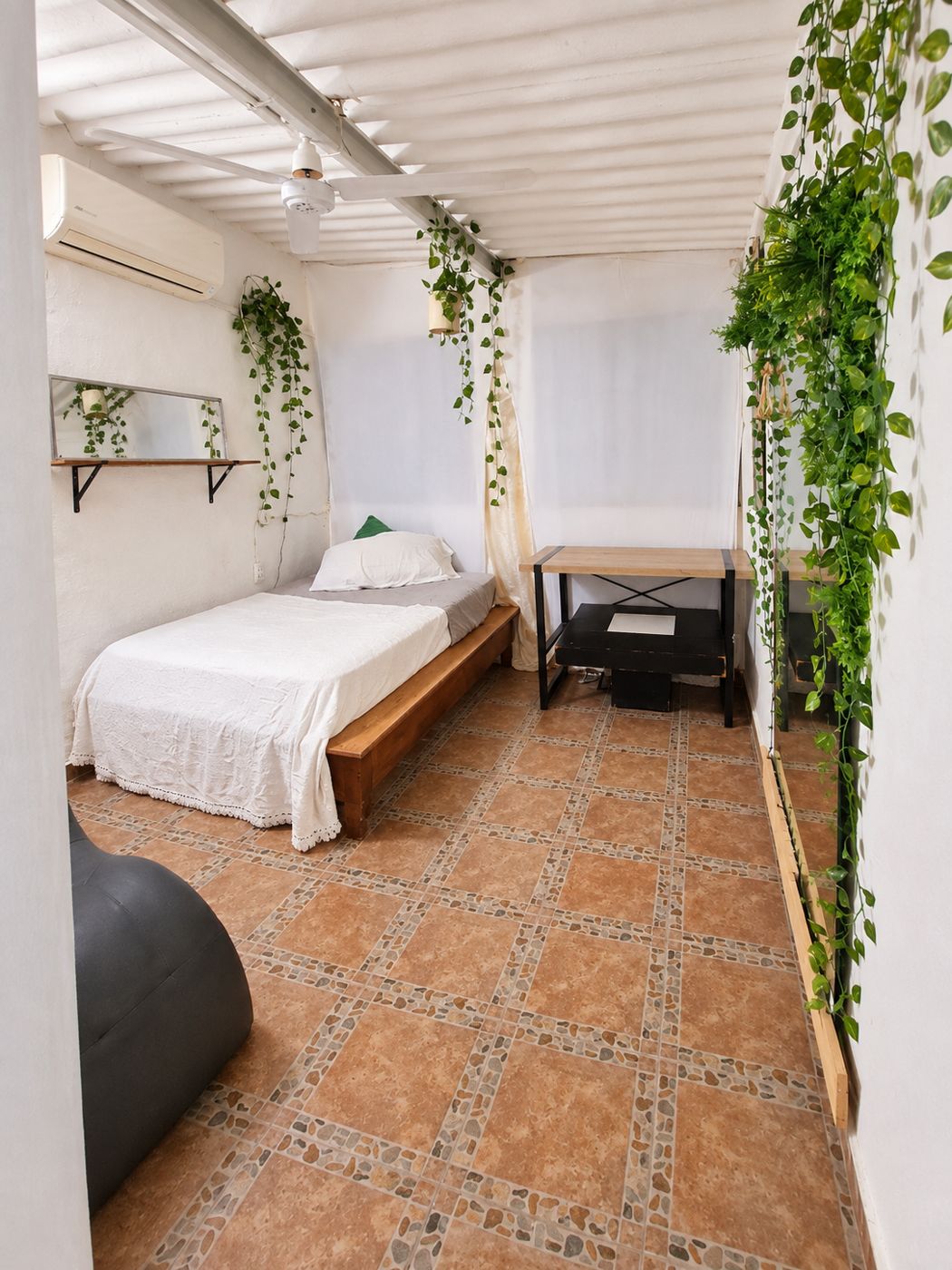 Habitación luminosa con cama, mesa y vegetación